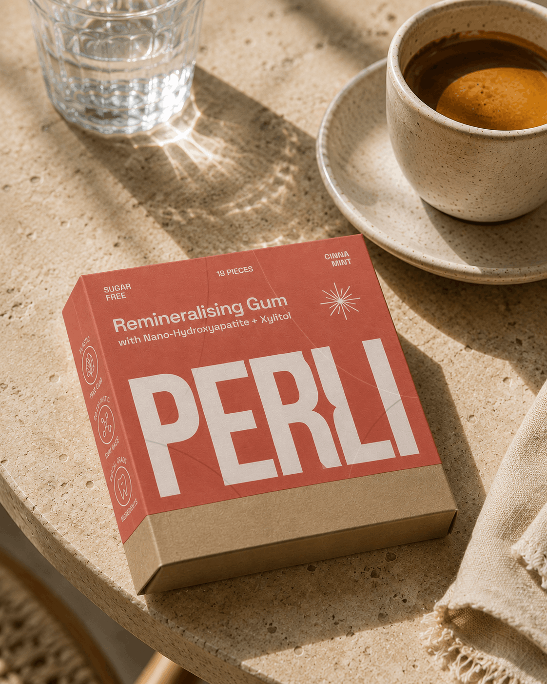 Perli Cinna Mint gum box on cafe table beside espresso and water