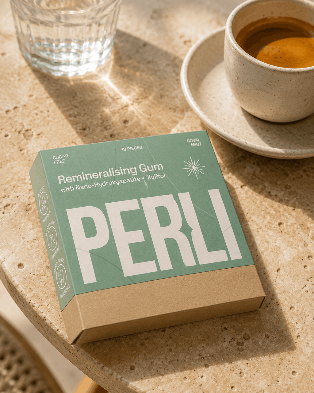 Perli Royal Mint gum box on cafe table beside espresso and water